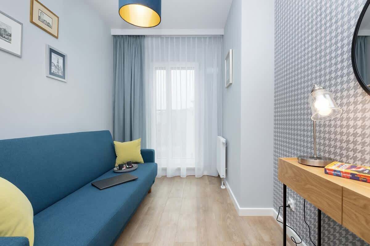 En moderne stue med en blå sofa, et træ sidebord og tapet med et mønster.