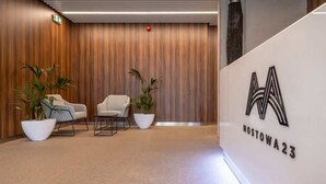 Una zona de recepción moderna con una pared de madera, dos sillas blancas y plantas en macetas.