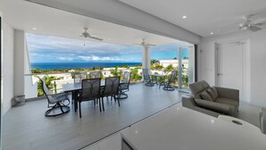 Un salon moderne doté d’une grande porte vitrée donnant sur un balcon avec vue sur l’océan.