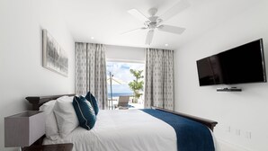 Une chambre d’hôtel avec un lit, une télévision, un ventilateur de plafond et une vue sur l’océan.