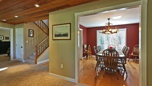 A dining area with a wooden table and chairs, a chandelier, and a staircase leading to another room. - Comfortable Shaver Lake Getaway (Shaver Lake)