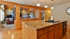 A spacious kitchen with wooden cabinets, granite countertops, and pendant lighting. - Comfortable Shaver Lake Getaway (Shaver Lake)