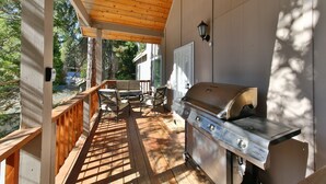 An outdoor patio with a grill, wooden deck, and a covered area with a table and chairs. - Comfortable Shaver Lake Getaway (Shaver Lake)