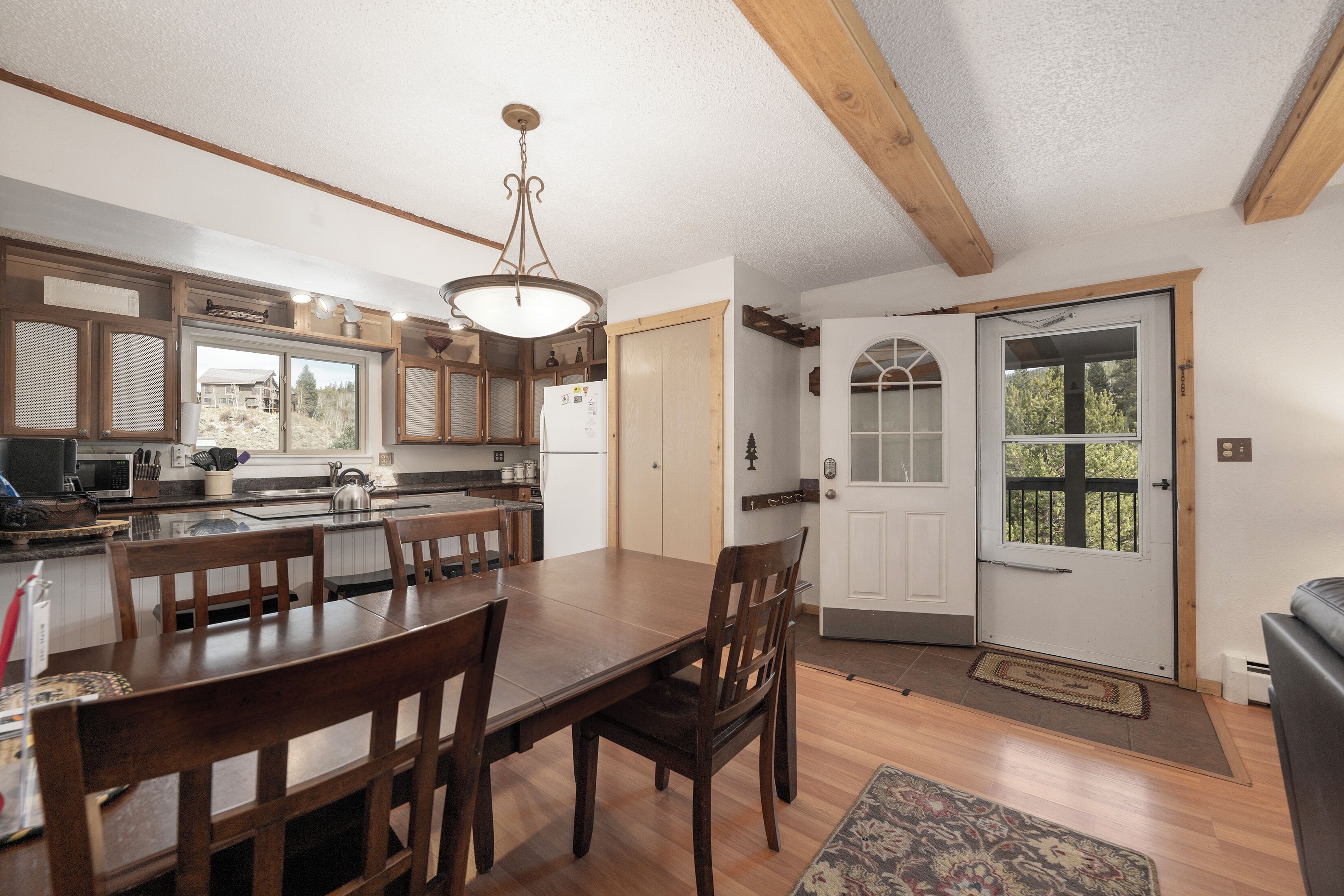 A spacious kitchen with wooden cabinets, a dining table, and a chandelier.