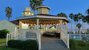 A gazebo with a covered seating area, steps leading up to it, and a pool in the background. - "The Erin" ~ a nautical condo with beach & pond view (Corpus Christi)