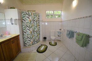 A bathroom with a shower curtain, toilet, sink, and towels.
