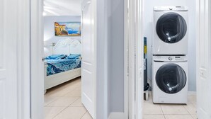 Quarto com uma cama, um quadro e duas máquinas de lavar empilhadas.