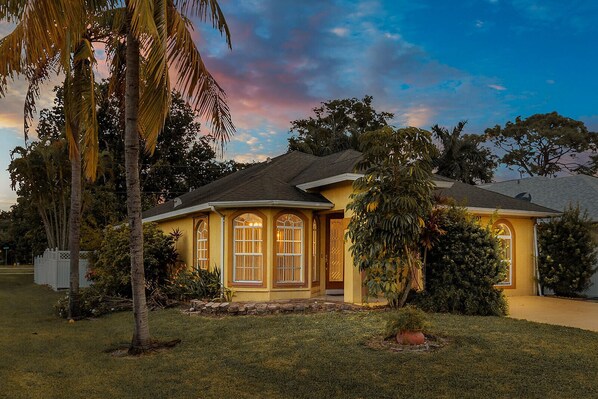 A single-story house with a yellow exterior, large windows, and a well-maintained lawn.