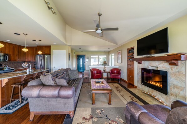 A spacious living area with a fireplace, a kitchen with modern appliances, and a comfortable seating arrangement. - Wapato Point Halmalka Condo 512B Sleeps 8 by Outdoor Pool, Sandy Beach Amenities (Manson)