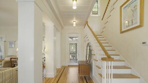 A hallway with a wooden floor, white walls, and a staircase with white railings. - Large Seaside Home, Tower w/ Gulf Views, Sleeps 12, 3 Min to Beach + 2 Bikes! (Santa Rosa Beach)