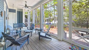 A covered porch with wooden flooring, blue Adirondack chairs, and a ceiling fan. - Large Seaside Home, Tower w/ Gulf Views, Sleeps 12, 3 Min to Beach + 2 Bikes! (Santa Rosa Beach)
