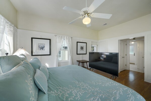 A bedroom with a bed, a TV, a ceiling fan, and framed pictures on the wall. - Large Seaside Home, Tower w/ Gulf Views, Sleeps 12, 3 Min to Beach + 2 Bikes! (Santa Rosa Beach)