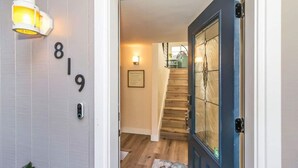 A hallway with a wooden staircase, a blue door, and a wall-mounted number sign '819'. - Seas the Day on the Bay (San Diego)