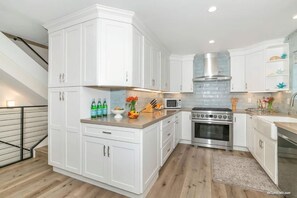 Enjoy cooking in this well-equipped kitchen with a stainless steel range, microwave, and white cabinetry.