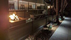 An outdoor patio area with a fire feature, seating, and a view of a house. - Seas the Day on the Bay (San Diego)
