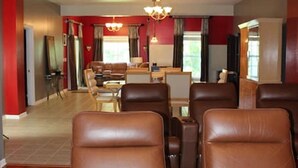 Een ruime kamer met leren loungestoelen, een eethoek en een kroonluchter.