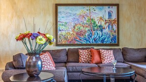 Una sala de estar con un sofá, una mesa de centro y un jarrón de flores.