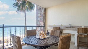 A balcony with a round table, wicker chairs, a small bar area, and a view of the ocean. - Sonoran Sky 308 Must-see Clean Bright Ocean View Condo (Puerto Peñasco)