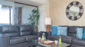 A living room with two grey sofas, a glass coffee table, a lamp, and a round mirror on the wall. - Sonoran Sky 308 Must-see Clean Bright Ocean View Condo (Puerto Peñasco)