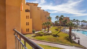 Een resort met een zwembad, palmbomen en een heldere lucht.