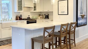 A modern kitchen with a central island, pendant lighting, and a framed map on the wall. - Stunning 3 bed/3bath Renovated Cabin on Lake Pepin (Frontenac)