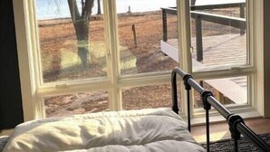 A bedroom with a large window offering a view of a lake and dock. - Stunning 3 bed/3bath Renovated Cabin on Lake Pepin (Frontenac)