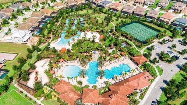 Ett flygbildsfoto av ett bostadsområde med en central pool, tennisbanor och ett välanlagt parkområde.