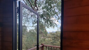 Una cabaña de madera con un balcón accesible mediante un vidrio.