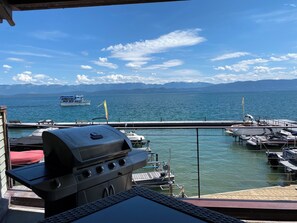 A view of a marina with boats docked, a grill, and mountains in the background.