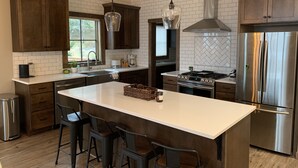 A modern kitchen with a large island, dark wooden cabinets, stainless steel appliances, and pendant lighting. - Newly built Mosier Bluff home-3 Bed, 3.5 Bath Spectacular River View and Hot Tub (Mosier)