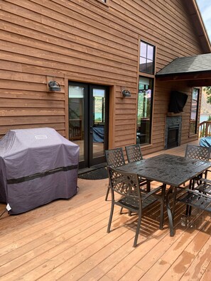 Eine Holzdiele mit überdachtem Grill, Gartenmöbeln und einem Kamin.
