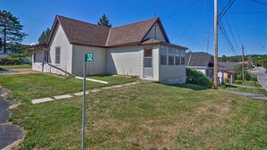 A single-story house with a brown roof and white siding, number 32, with a front yard and a visible driveway.