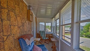A room with a stone wall, a blue sofa, a rocking chair, and a view of the outside.