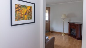 A room with a framed picture of a butterfly, a lamp, and a fireplace.