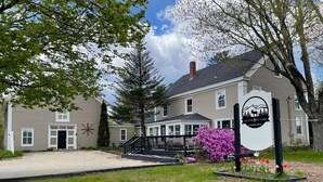 A two-story building with a porch and a sign that reads "The LUNJUL Lodge Sunday River."