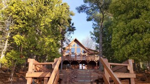 A wooden cabin with a balcony, surrounded by trees.