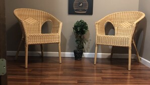 Two wicker chairs with curved backs and armrests, a potted plant, and a framed artwork on the wall. - Silver Lake Cabin (Traverse City)