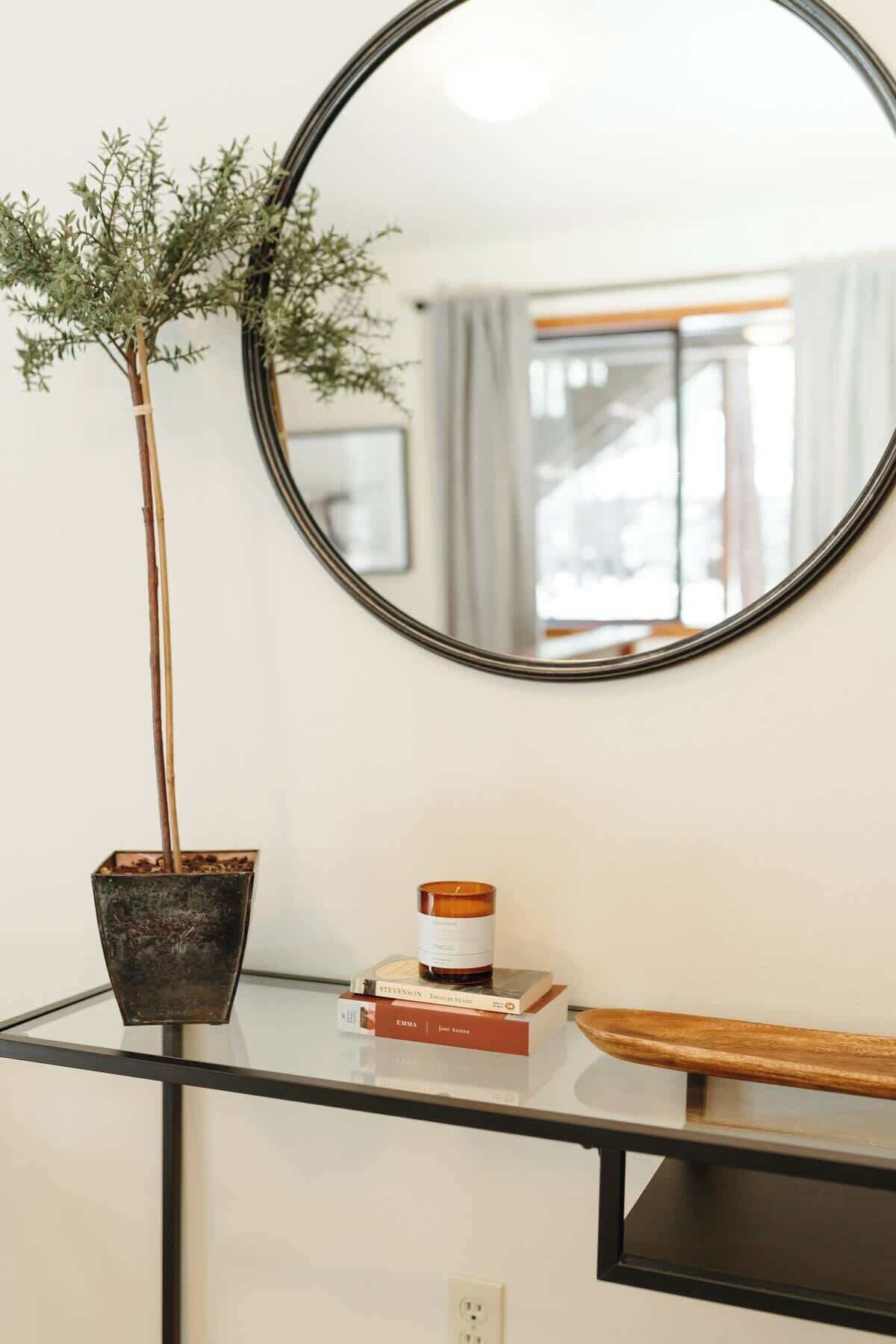A glass table with a potted plant, a candle, and books.