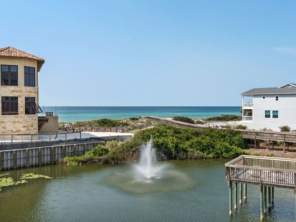 A waterfront property with a fountain, a wooden deck, and a view of the ocean.