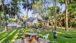 A house with a patio area featuring a picnic table and chairs, surrounded by trees.