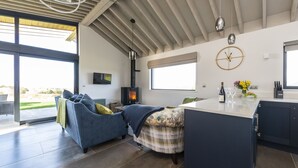 Una cocina moderna con una isla grande, estufa integrada y un comedor con un sofá azul y una pequeña mesa.