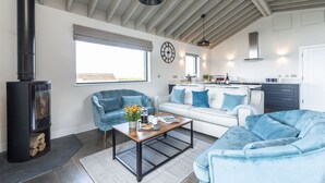 A modern living room with a fireplace, two sofas, a coffee table, and a kitchen in the background. - Dorset Eco Retreats - Ansty, Dorchester (Ansty, Dorchester)