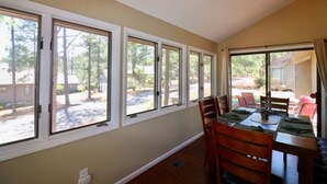 Comedor con una mesa dispuesta para cuatro, ventanas amplias en una pared y vista a una zona residencial.