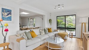 A modern living room with a sectional sofa, a glass coffee table, and a dining area with a wooden table and chairs.