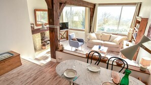 A dining area with a table set for four, a sofa, and a TV in the background. - Nice apartment for 3 guests with WIFI, TV and panoramic view (Tourgeville)
