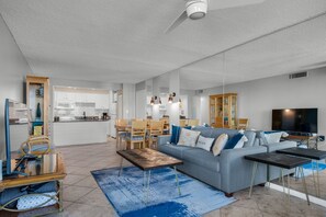 Un salon moderne avec un canapé gris, une table basse en bois et un téléviseur.