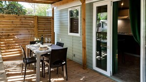 A covered patio with a dining table and chairs, a wooden fence, and a sliding glass door leading to a kitchen area. - Lovely apartment in villa for 5 people with A/C, WIFI, pool, terrace and pets allowed (Bibbona)