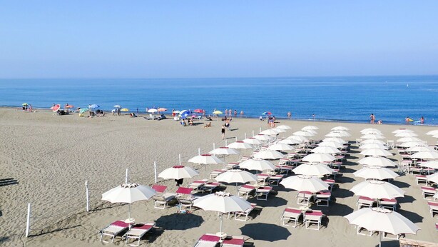 A beach with rows of beach chairs and umbrellas, a clear sky, and the ocean in the background. - Lovely apartment in villa for 5 people with A/C, WIFI, pool, terrace and pets allowed (Bibbona)