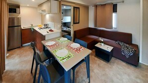 Un espace de vie compact comprenant un coin cuisine, un coin repas et un coin salon.