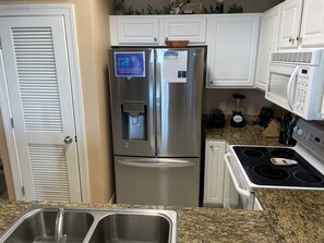 A kitchen with stainless steel appliances, a water dispenser, a microwave, and a stove. - Great Weekly Rate With Beachfront Views (Panama City Beach)